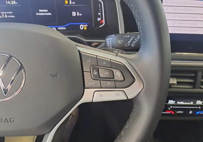 Gros plan sur le volant côté gauche du Volkswagen Taigo gris cendre, avec commandes multifonctions et tableau de bord numérique.