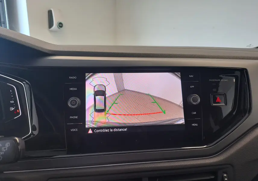 Écran de caméra de recul du Volkswagen Taigo gris cendre 2025, affichant les lignes de guidage et l'alerte de distance.