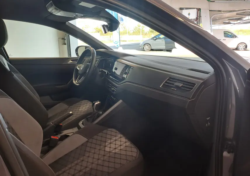 Vue intérieure côté conducteur du Volkswagen Taigo gris cendre 2025, avec sièges tissu à motifs et tableau de bord moderne.