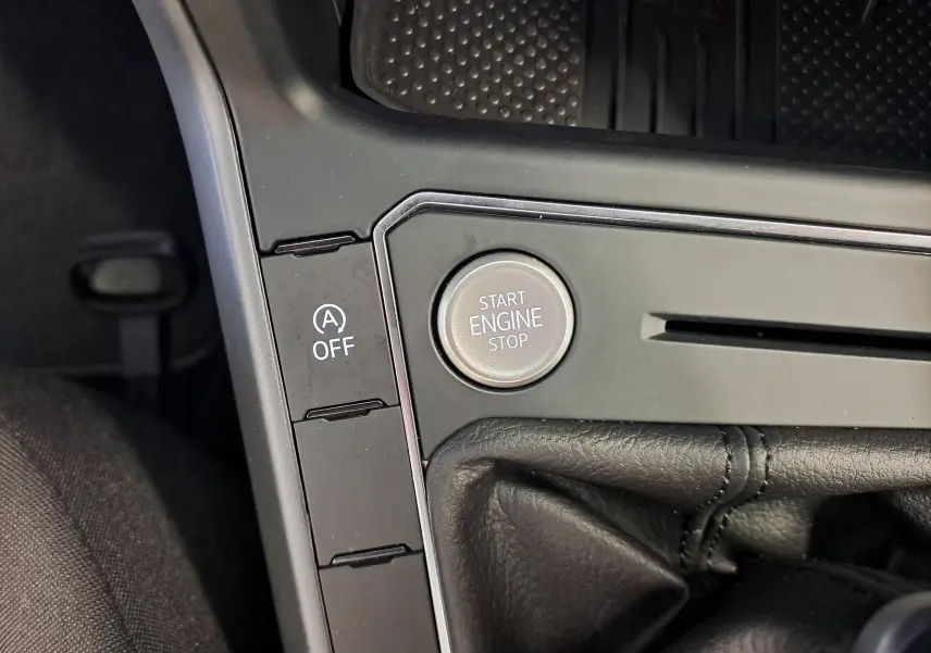 Gros plan sur le bouton Start Engine Stop et la commande Auto Start-Stop désactivée dans l'habitacle du Volkswagen Taigo gris cendre.