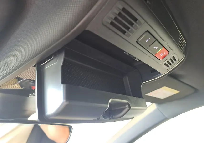 Rangement lunettes ouvert au plafond intérieur d’un Volkswagen Taigo gris cendre, avec commandes d’assistance visibles.