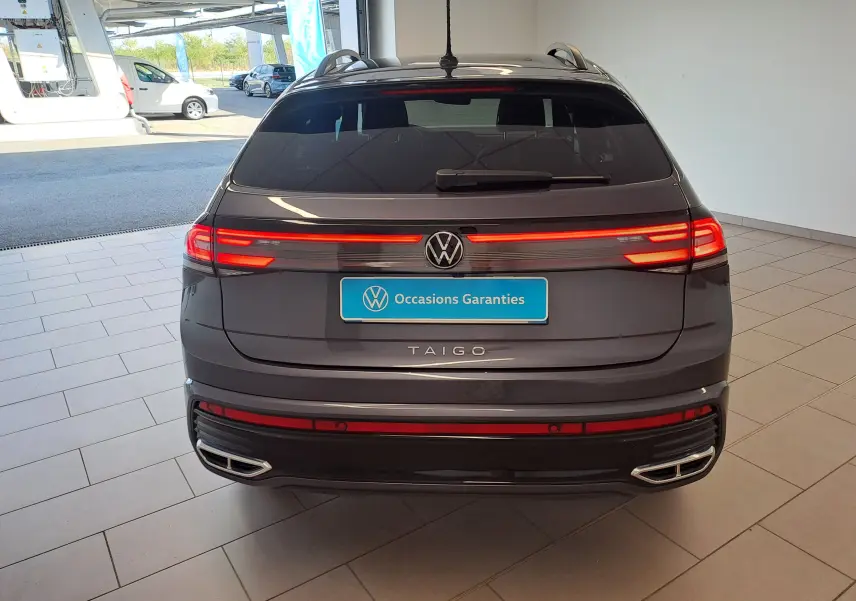 Vue arrière d'un Volkswagen Taigo gris cendre avec feux LED allumés et double sortie d'échappement intégrée.