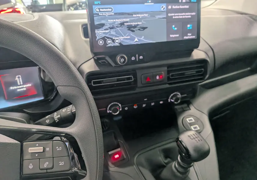 Vue intérieure du tableau de bord du Citroën Berlingo 2025 blanc, avec écran tactile et levier de vitesse manuel visible.