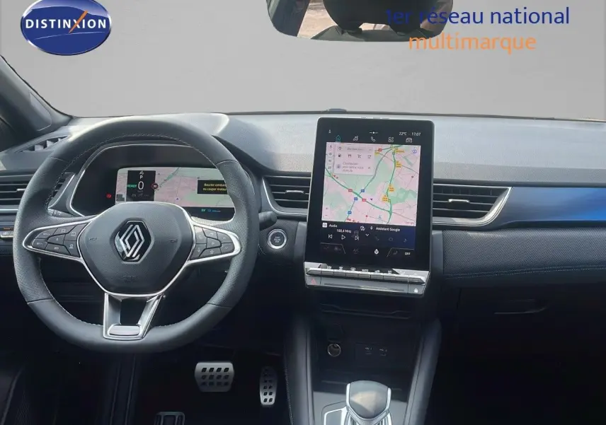 Intérieur de Renault Captur E-Tech hybride 2025, vue du poste de conduite avec écran tactile central et volant noir.