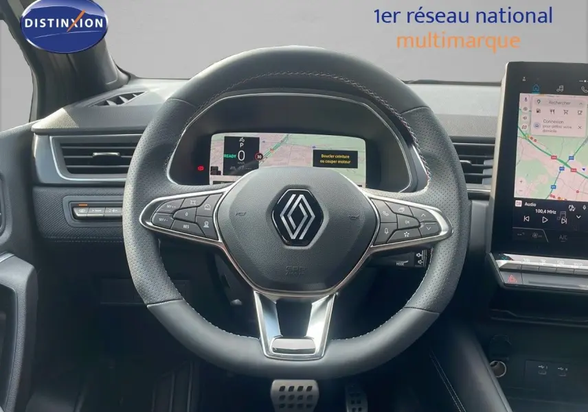 Vue centrée sur le volant en cuir noir perforé du Renault Captur E-Tech 2025 avec tableau de bord numérique et écran tactile.