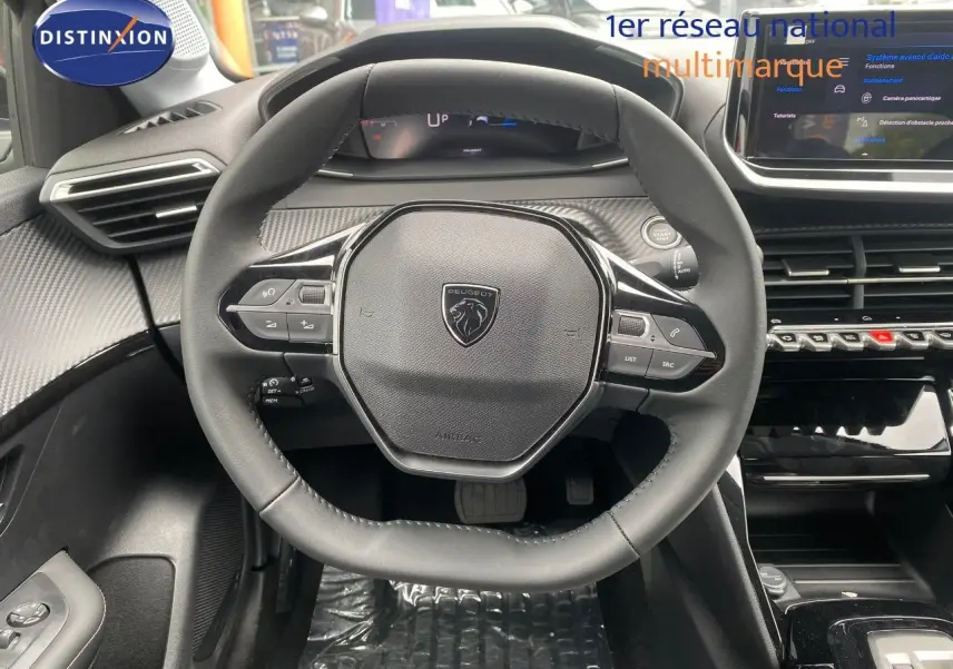 Vue intérieure centrée sur le volant cuir noir de la Peugeot 208 Hybrid 145ch avec tableau de bord et écran tactile.