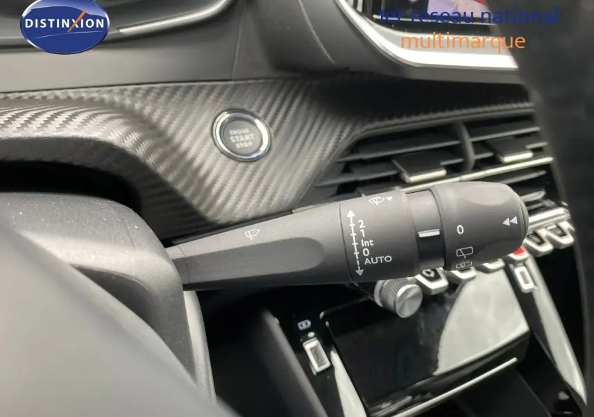 Gros plan sur la commande d’essuie-glace et le bouton start/stop, tableau de bord carbone du Peugeot 208 gris selenium.