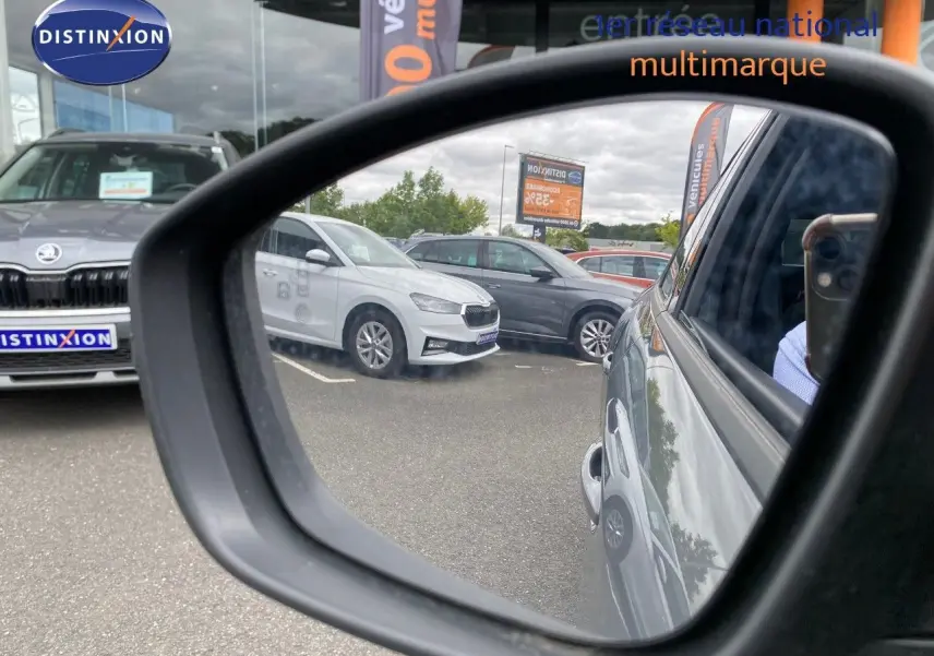 Rétroviseur droit montrant la Peugeot 208 Hybrid gris selenium métal vue de côté droit sur un parking multimarque.