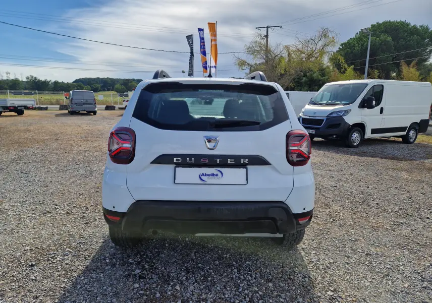 Vue arrière d'un Dacia Duster blanc 2023, avec feux arrière distinctifs et logo Duster bien visible.