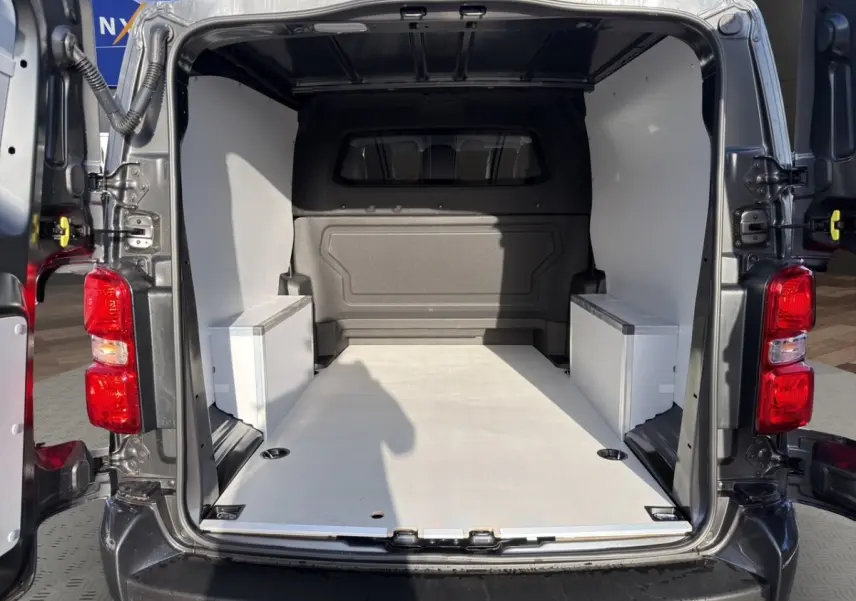Vue arrière ouverte du Peugeot Expert Fourgon XL gris foncé, montrant l'espace de chargement vide avec cloison vitrée.