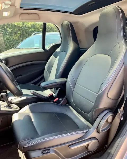 Intérieur du Smart Fortwo électrique 2019, sièges en cuir noir et gris, vue côté conducteur avec toit panoramique ouvert