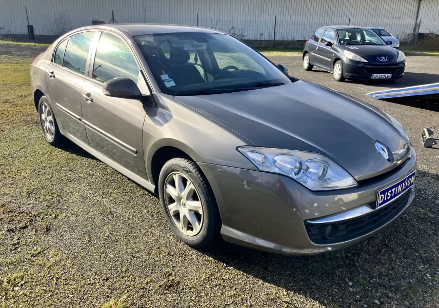 Renault Laguna 1.5l dCi 110 ch gris vert vue 3/4 avant droit sur un parking ensoleillé.