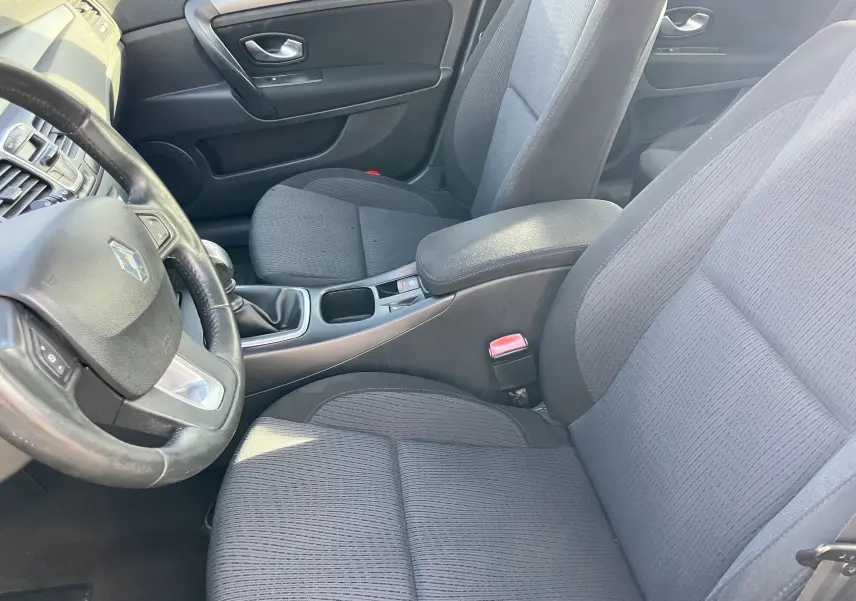 Intérieur noir tissu de la Renault Laguna 2008, vue côté conducteur montrant volant, sièges et console centrale.