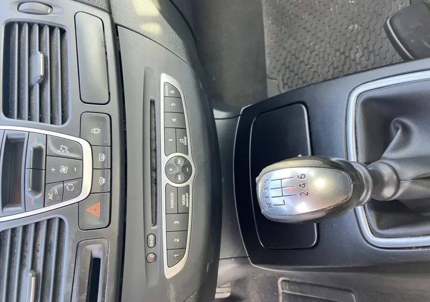 Vue rapprochée de la console centrale d'une Renault Laguna gris vert 2008, mettant en valeur le levier de vitesses manuel à six rapports.