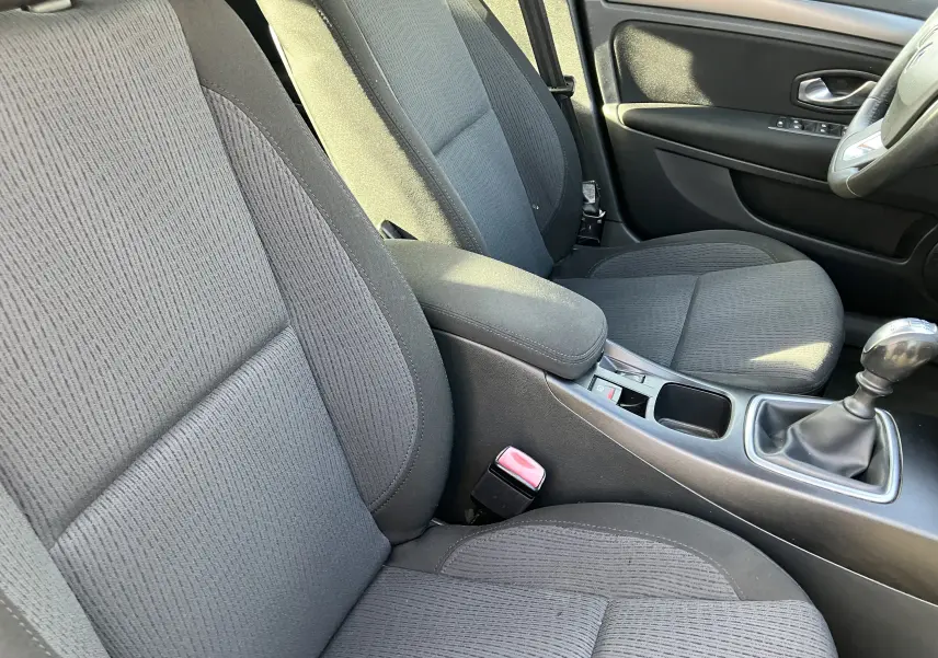 Intérieur avant de la Renault Laguna 1.5l dCi 2008, sièges en tissu noir et levier de vitesses manuel visible côté droit.