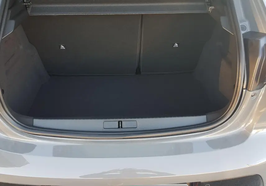 Coffre ouvert vu de l'arrière d'une Peugeot 208 Hybrid gris 2024, montrant l'espace de chargement vide.
