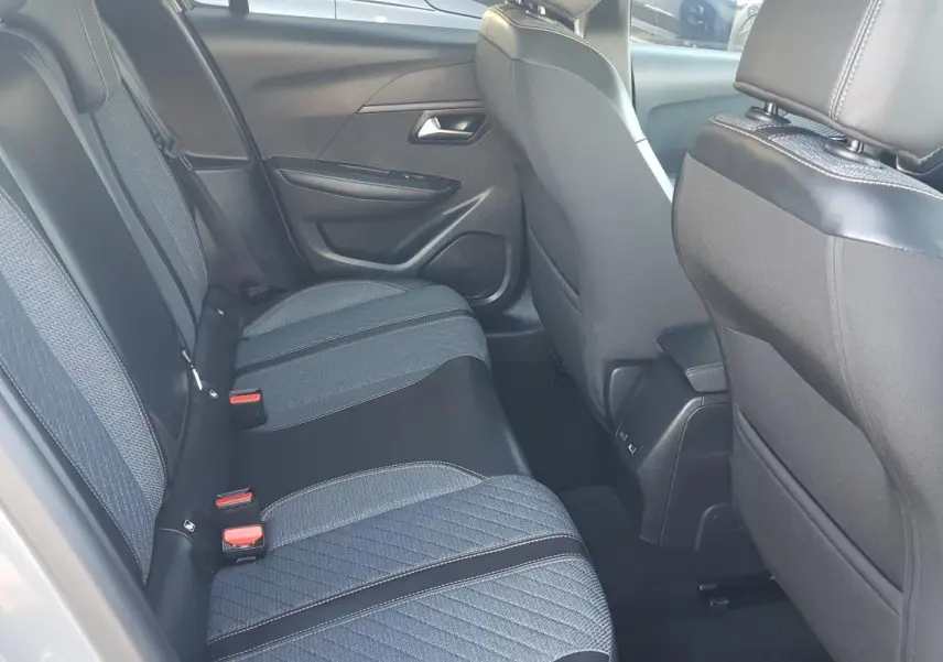 Vue intérieure des sièges arrière gris foncé et tissu texturé d'une Peugeot 208 Hybrid 2024, côté gauche.