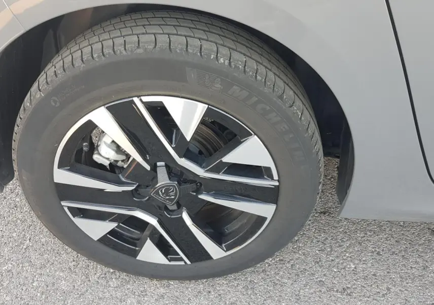 Gros plan sur la jante alliage 16 pouces noire et grise du côté gauche d'une Peugeot 208 gris 2024.