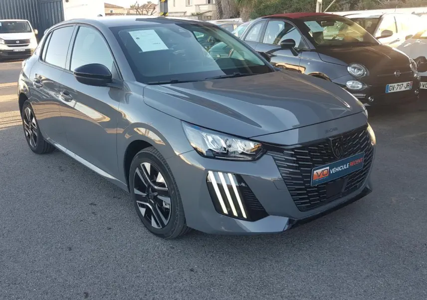Peugeot 208 Hybrid gris vue 3/4 avant droit, avec calandre noire et feux diurnes à LED verticaux.
