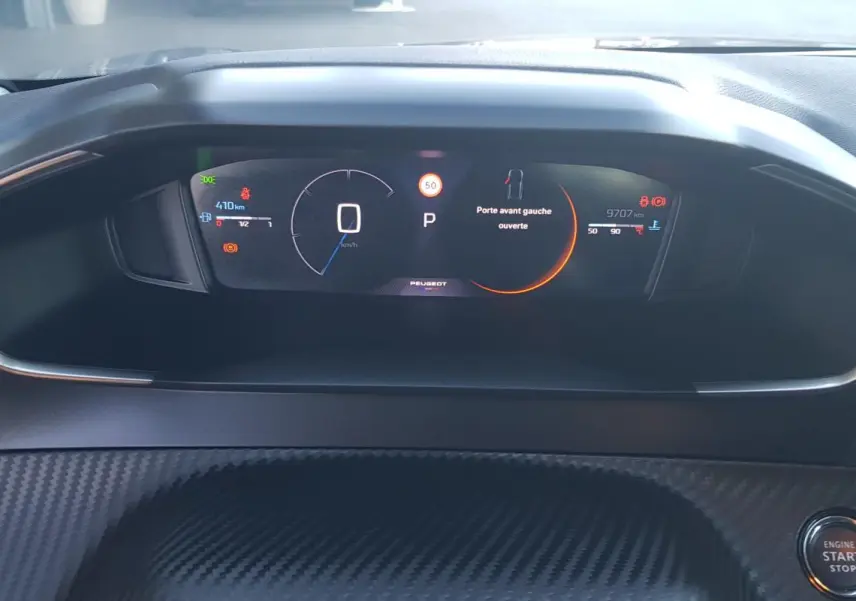 Vue rapprochée du cockpit numérique de la Peugeot 208 Hybrid 2024, affichant vitesse et alertes sur fond noir.