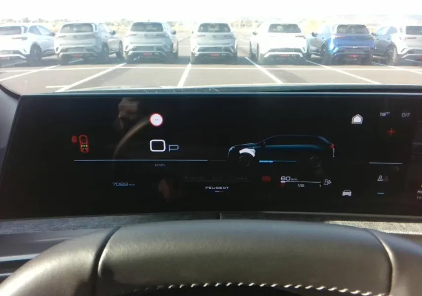 Vue intérieure du tableau de bord numérique du Peugeot 5008 hybride, affichant l'autonomie et la vitesse, avec volant en premier plan.