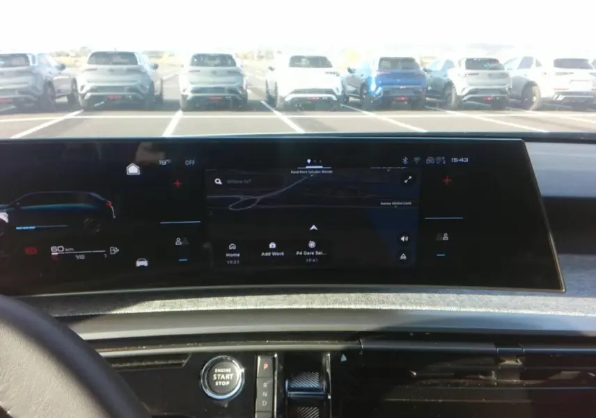 Vue intérieure du tableau de bord du Peugeot 5008 bleu foncé 2025, avec écran panoramique incurvé et console centrale noire brillante.