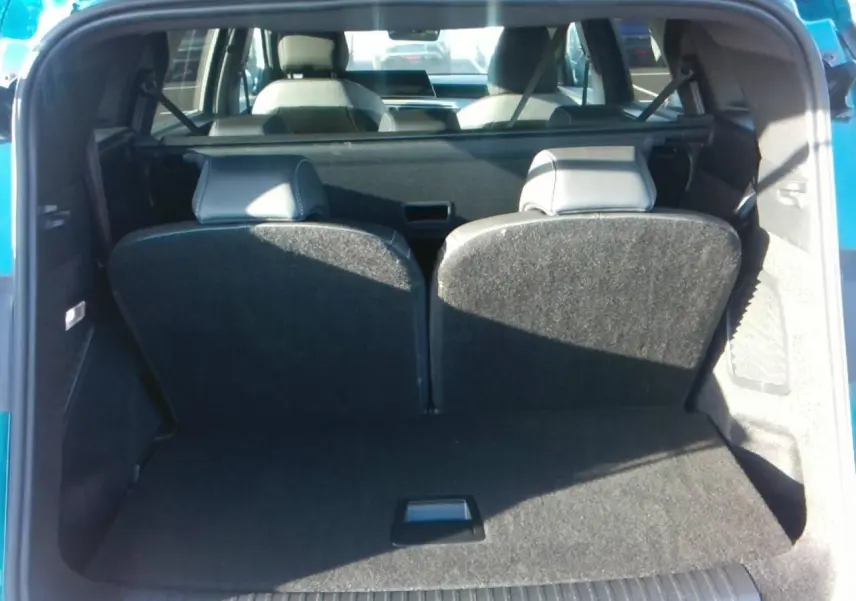 Vue arrière du coffre ouvert d'un Peugeot 5008 bleu foncé, montrant la banquette arrière relevée et l'intérieur spacieux.