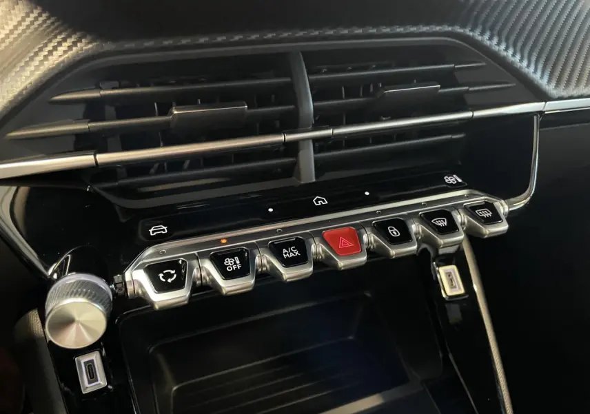 Gros plan sur la console centrale noire brillante du Peugeot 2008 2026 avec boutons de commande et ventilation.