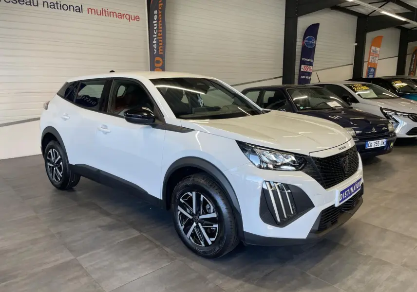 Peugeot 2008 blanc en 3/4 avant droit, avec calandre noire et jantes alliage bicolores en showroom.