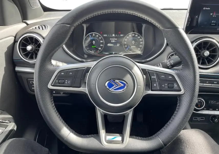 Vue centrée sur le volant en cuir perforé du SERES 3 Luxury noir métal avec tableau de bord numérique et écran tactile.