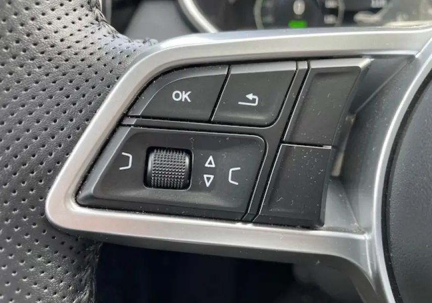 Gros plan sur les commandes multifonctions noires et argentées du volant en cuir perforé du SERES 3 Luxury 2022.