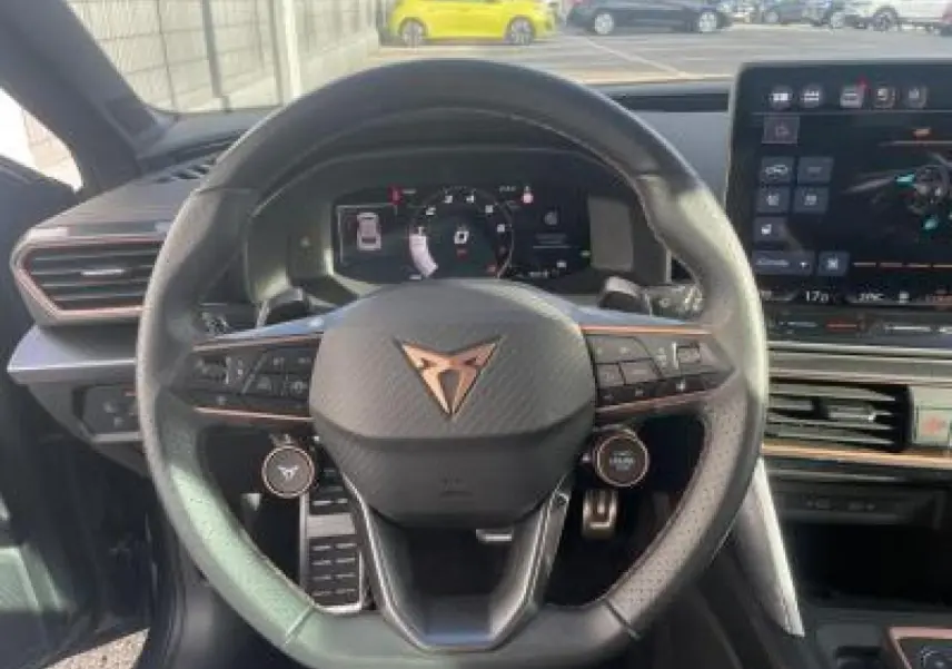 Vue centrée sur le volant cuir noir du CUPRA Leon 2025 avec logo cuivré et tableau de bord digital visible