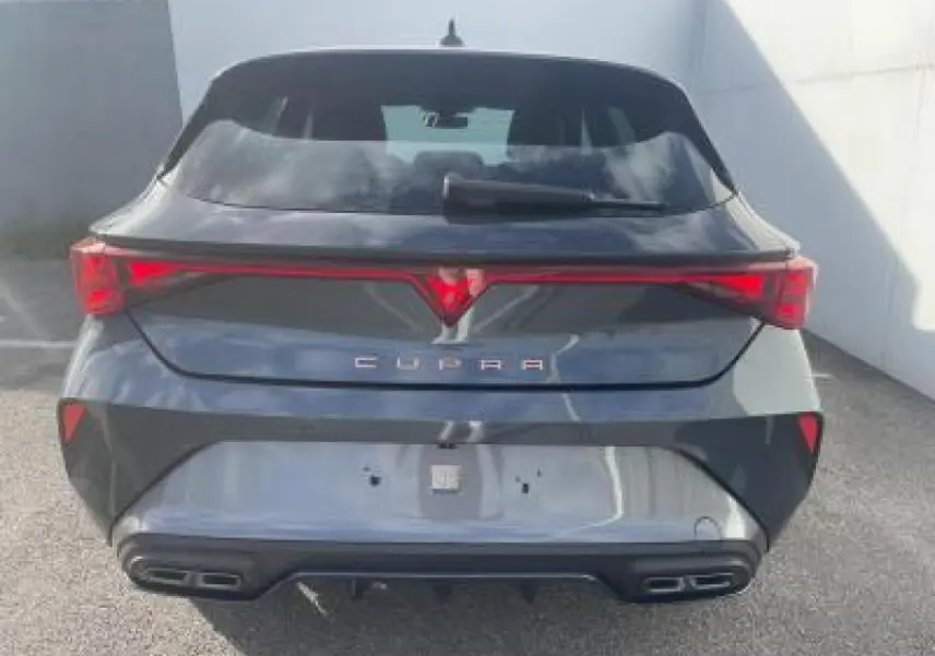 Vue arrière d'une CUPRA Leon 2025 gris magnetic metal avec bandeau lumineux et double sortie d'échappement noire stylisée.