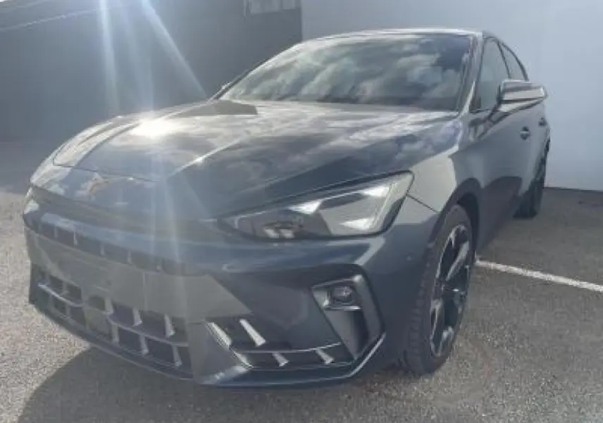 Vue 3/4 avant d'une CUPRA Leon 2025 gris magnetic metal avec jantes alliage noires et signature lumineuse Tri-LED.