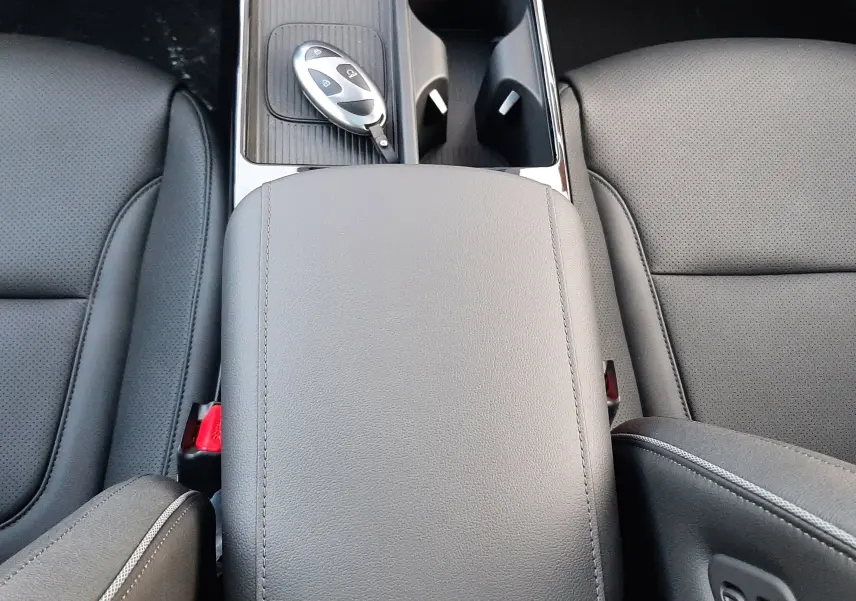 Vue plongeante sur la console centrale cuir gris et la clé digitale du Hyundai Tucson 2025 hybride, sièges noirs perforés.