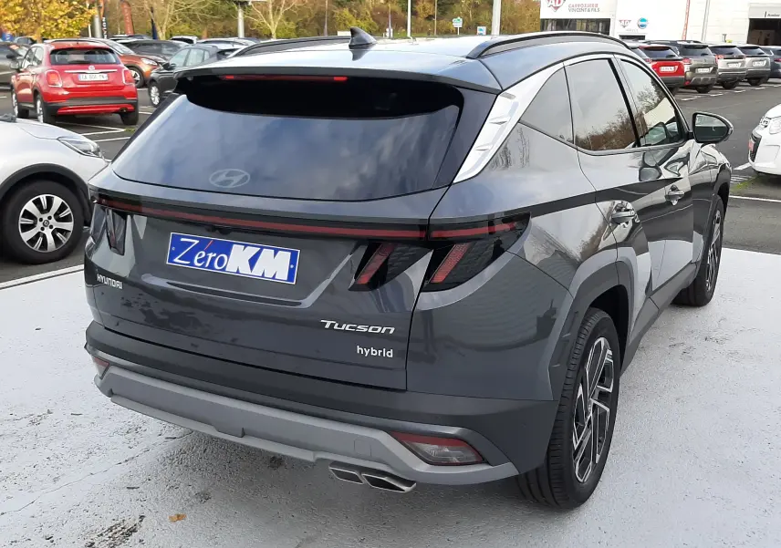 Vue 3/4 arrière droite du Hyundai Tucson hybride gris Ecotronic avec feux LED et double sortie d'échappement visible.