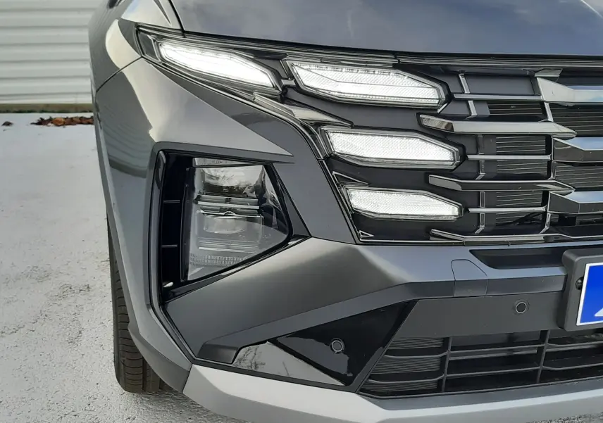 Gros plan sur l'avant gauche du Hyundai Tucson 2025 gris Ecotronic, mettant en valeur ses phares LED Matrix et sa calandre distinctive.