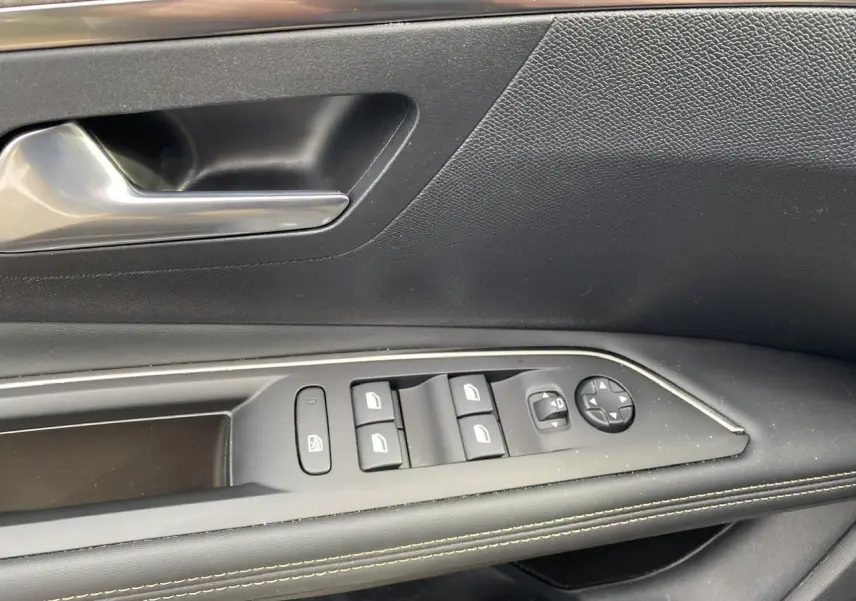 Gros plan sur la commande de lève-vitres et rétroviseurs côté conducteur du Peugeot 3008 gris foncé 2023.