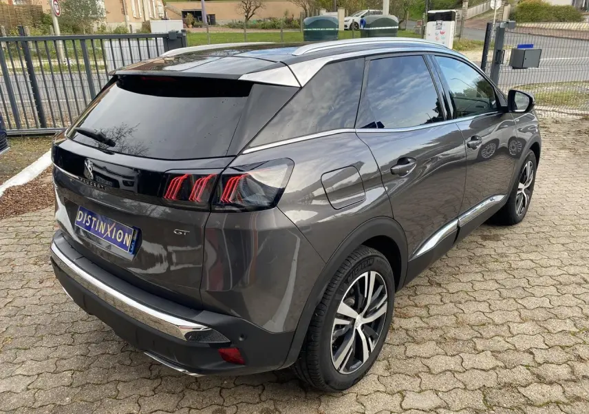 Peugeot 3008 gris foncé en 3/4 arrière droit, avec feux arrière LED et coques de rétroviseurs noires.