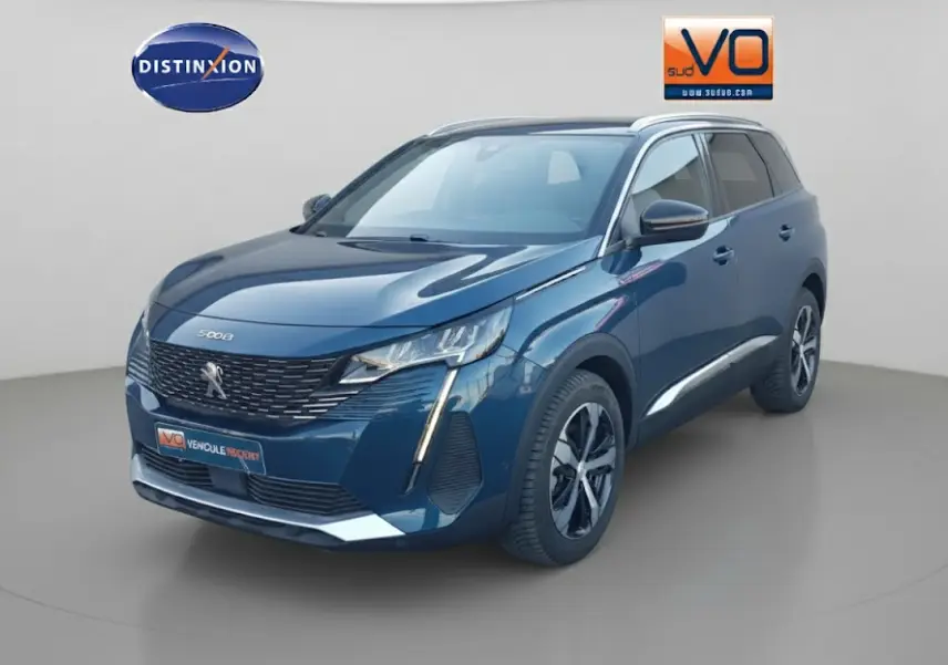 Peugeot 5008 bleu en 3/4 avant droit, avec jantes alliage 18 pouces et barres de toit visibles.