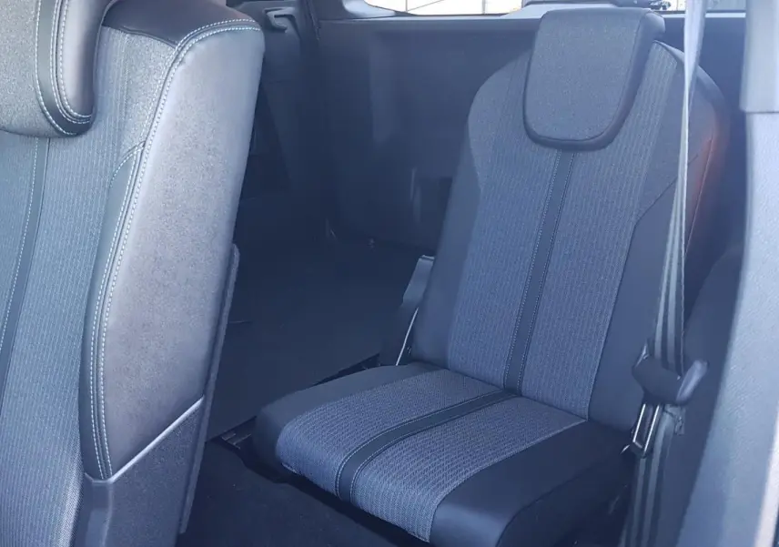 Vue intérieure sur les sièges arrière en tissu gris et noir du Peugeot 5008 bleu, avec ceinture de sécurité visible.