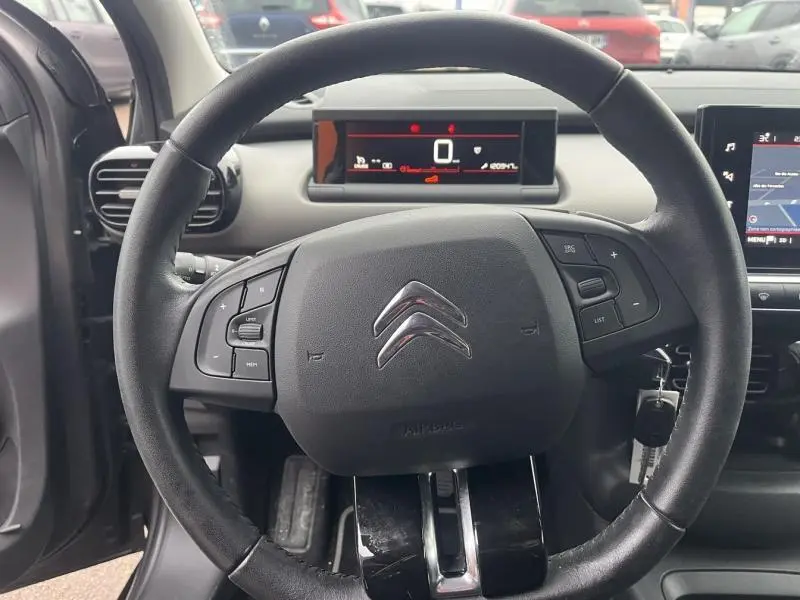 Vue intérieure centrée sur le volant noir de la Citroën C4 Cactus 2020 avec tableau de bord numérique en arrière-plan.