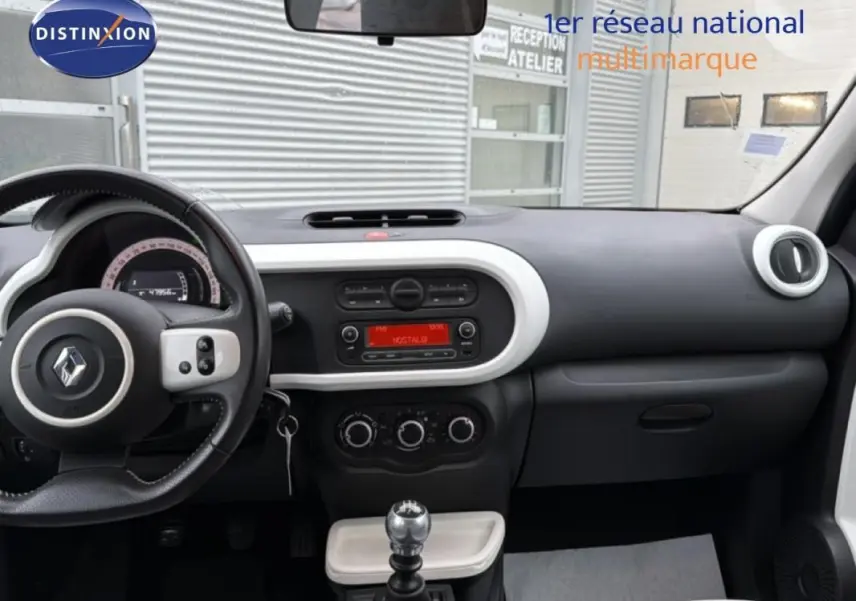 Vue intérieure du tableau de bord de la Renault Twingo III gris foncé, avec volant cuir et commande manuelle de vitesses.