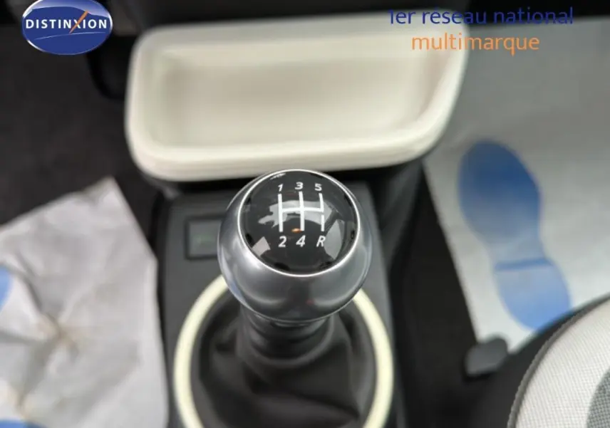 Gros plan sur le levier de vitesses manuel de la Renault Twingo III gris foncé, intérieur clair avec console beige.