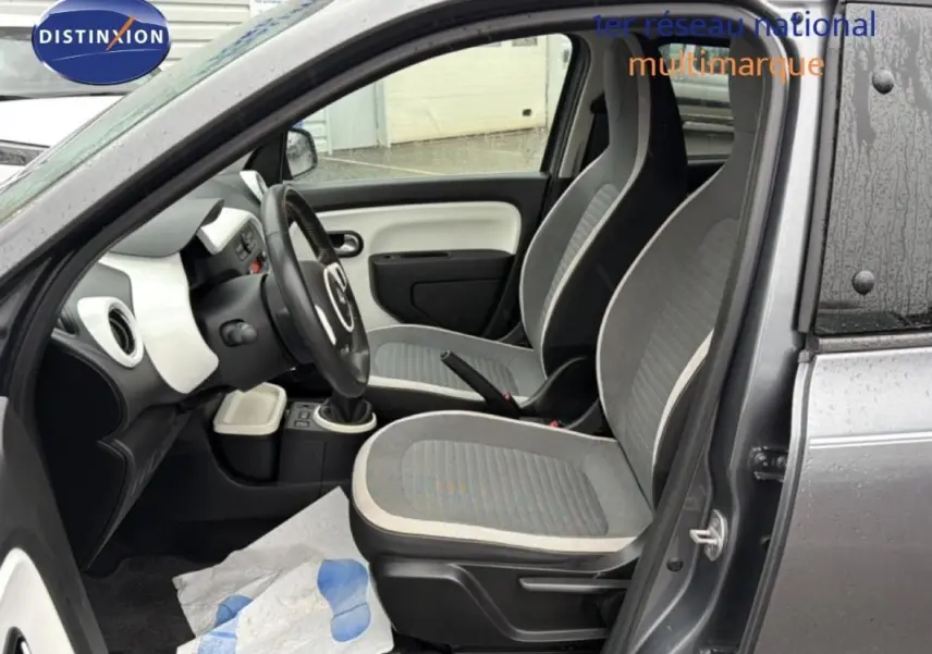 Vue intérieure côté conducteur de la Renault Twingo III gris foncé, montrant les sièges et le volant cuir.
