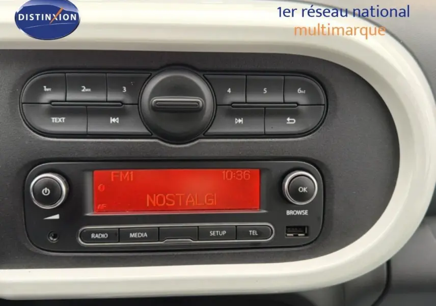 Tableau de bord de Renault Twingo III gris foncé, affichage radio rouge et commandes audio visibles en gros plan.