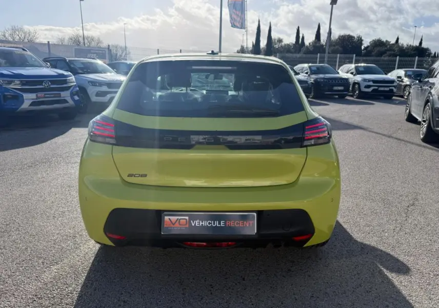 Vue arrière d'une Peugeot 208 jaune 2025 garée en extérieur, avec feux arrière LED et logo distinctif visible.