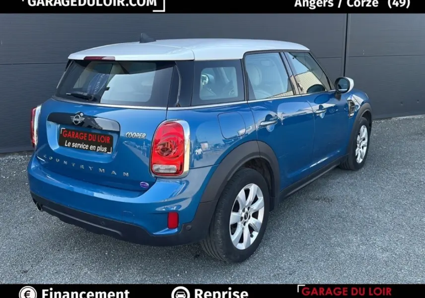 Vue 3/4 arrière droite d'une MINI Countryman Cooper bleu avec toit blanc, feux arrière distinctifs et jantes argentées.