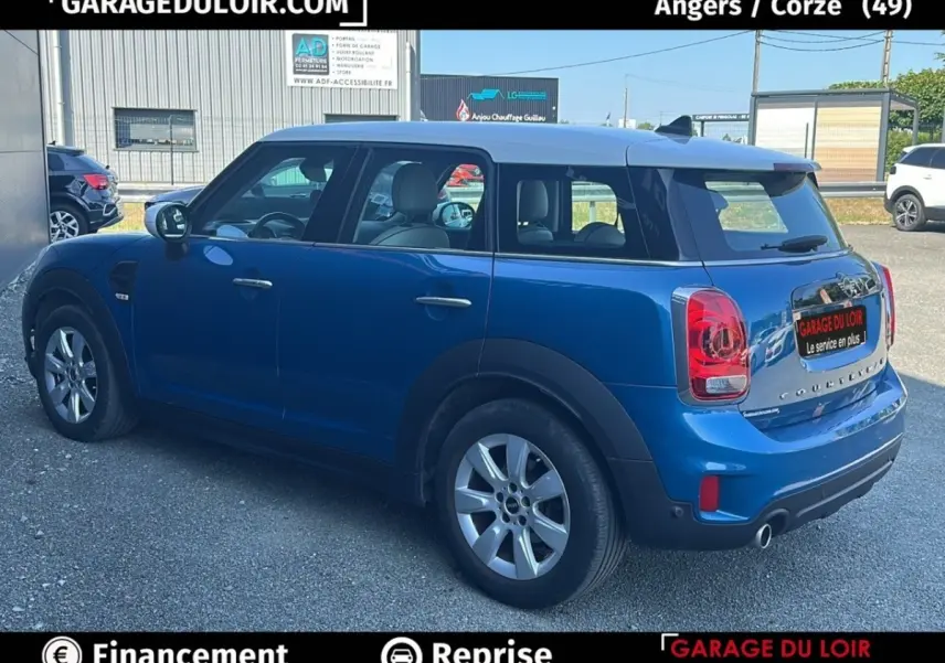 Vue 3/4 arrière droite d'une MINI Countryman Cooper bleu avec toit blanc et feux arrière LED, stationnée en extérieur.