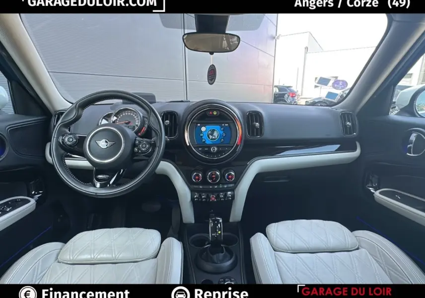 Vue intérieure avant du tableau de bord et volant cuir noir du MINI Countryman Cooper bleu avec sièges blancs.